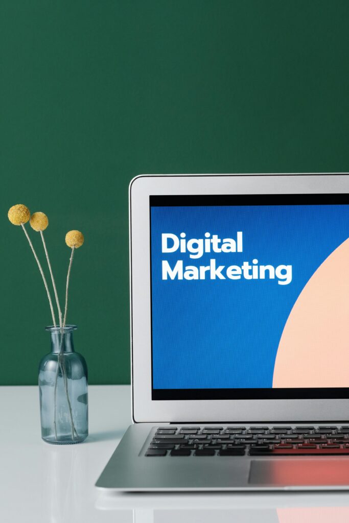 Discover the Powerful Digital Marketing Meaning | Top 10 Guide. A laptop displaying 'Digital Marketing' with a minimalist floral decor in a glass vase.
